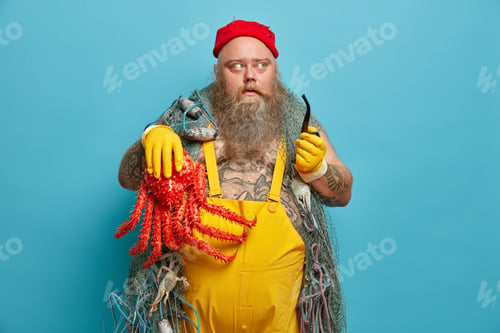 Preview: Thoughtful bearded man holds smoking pipe and octopus, enjoys favorite hobby. Fat successful fisherm