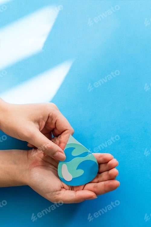 Preview: Vertical shot of female hands holding an abstract paper cut water drop on blue background
