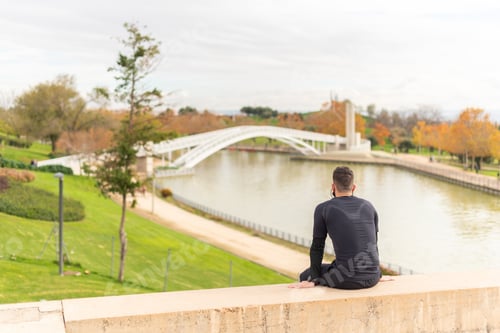Preview: Sportsman sitting with his back to camera in a park.