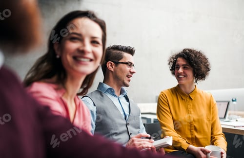 Preview: Group of young businesspeople working together in office, talking.