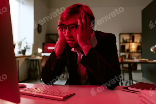 Preview: Young Caucasian Man Wearing Glasses Sitting at Desk Feeling Stressed