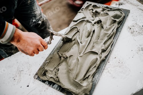 Preview: Facade builder working on stone tiles. Details of worker using mortar for stone installation