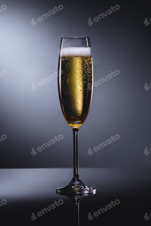 Preview: close up view of glass of champagne with foam on dark backdrop