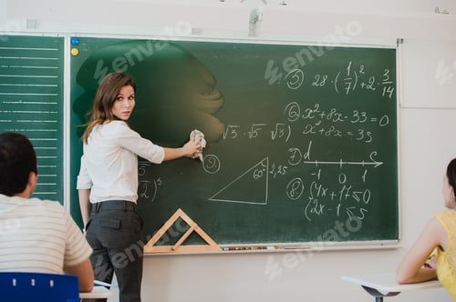 Preview: Female teacher at high school washes the chalkboard and lookng to the people in class