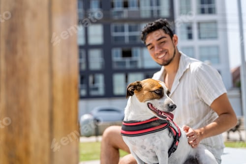 Preview: Young man petting his dog in a city park