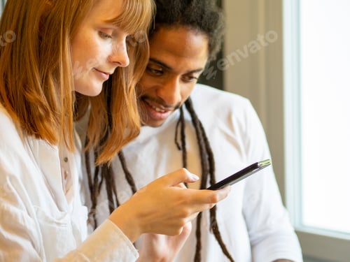 Preview: Interracial couple prepare a salad together with the help of their cell phone.
