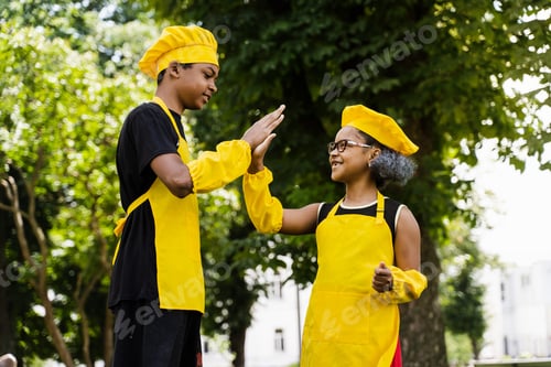 Preview: Black kids in chef uniforms giving five, promoting fun cooking activity for restaurants