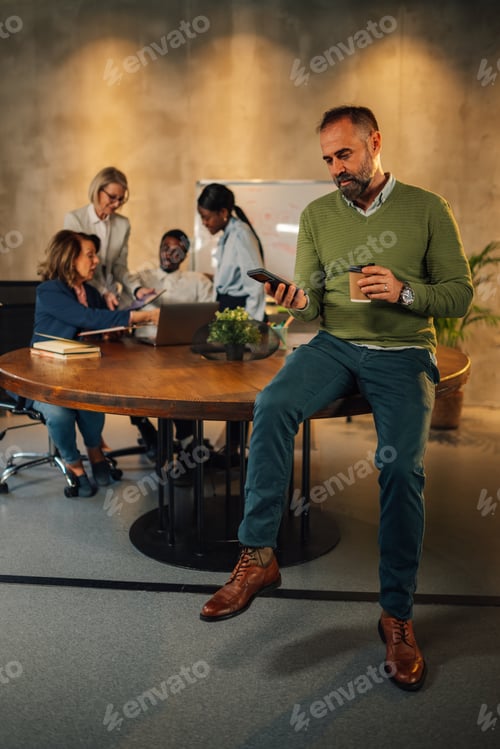 Preview: Executive with phone at boardroom on meeting of interracial staff.