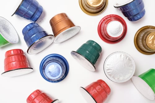Preview: Multi-colored capsules for coffee machine close-up on white background, top view.