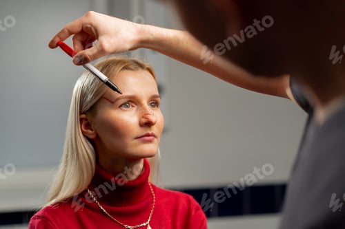 Preview: in a plastic surgery clinic doctor makes markings on the face of a young girl before surgery