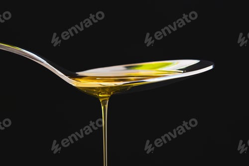 Preview: Olive oil liquid on a spoon over black background. Cuisine