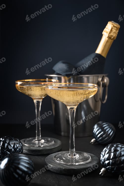 Preview: Festive New Year champagne in wine glasses and Christmas blue baubles on black background. Close up.