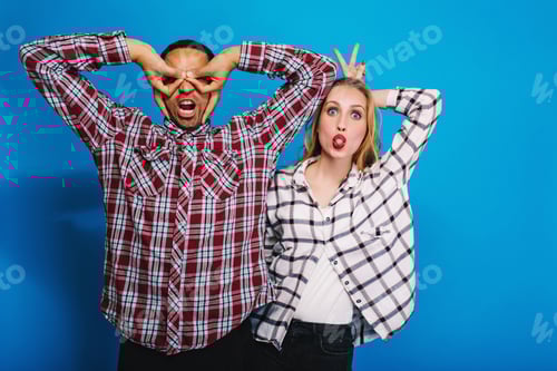 Preview: Expressing brightful positive emotions of funny excited couple having fun on blue background. Foolin