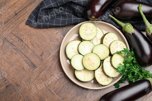 Preview: Slices of fresh eggplants, whole ones and parsley on wooden table, flat lay. Space for text