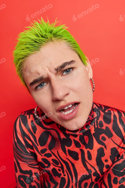 Preview: Close up shot of displeased indignant woman with short green hair looks attentively at camera reacts