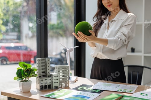 Preview: Woman holding green sphere planning sustainable city future
