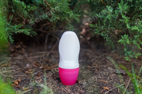 Preview: Natural deodorant with pink cap on green nature background. Space for text
