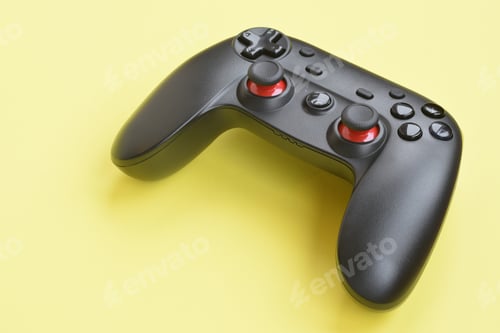 Preview: Modern black joystick on yellow background close up. Video game challenges and competitions concept