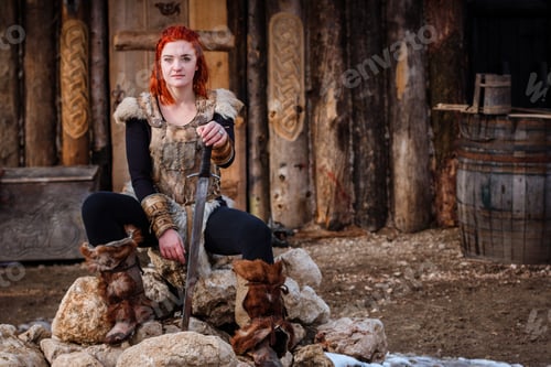 Preview: Red-haired woman is a Viking. Against backdrop of a village or an ancient settlement.