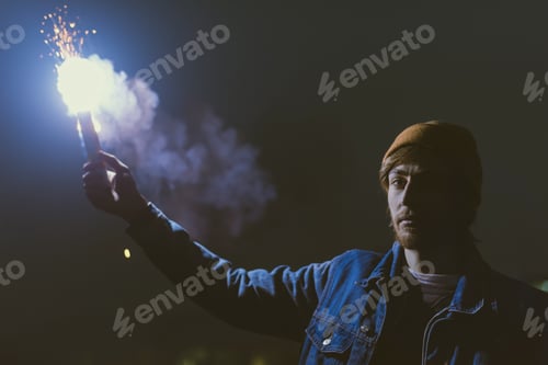 Preview: man holsing smoke bomb with sparks at night