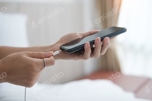 Preview: hands charging battery in mobile smart phone in the bedroom at home