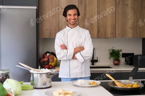 Preview: Indian chef smiling with arms crossed in a modern kitchen