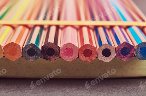 Preview: Multicolored pencils lying on a yellow notepad.