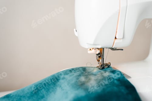 Preview: Part of a sewing machine with a needle and a thread pulled into it close-up