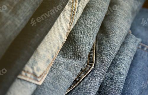 Preview: Many jeans in stack in wardrobe room. Row of pants denim jeans in closet