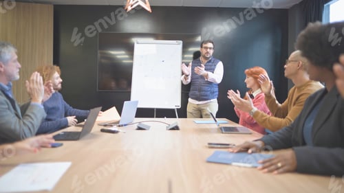 Preview: Business team applauding a colleague's presentation in a modern meeting room.