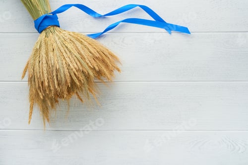 Preview: Shavuot jewish holiday celebration. Bouquet of golden ripe wheat with a blue ribbon. White wood boar