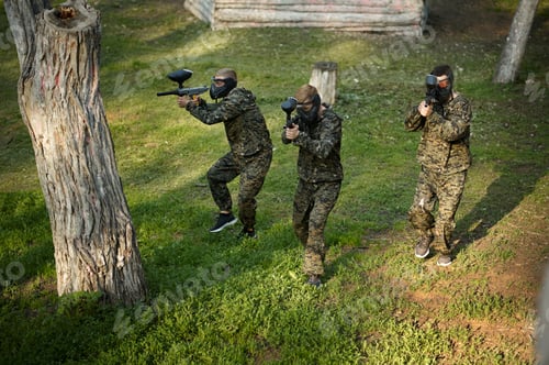 Preview: Team in uniform playing paintball in the forest