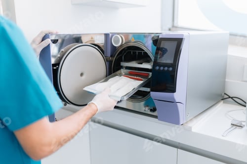 Preview: Dentist assistant sterilizing equipment in a machine