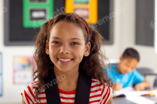 Preview: In school, young biracial female student smiling, wearing a striped shirt in classroom