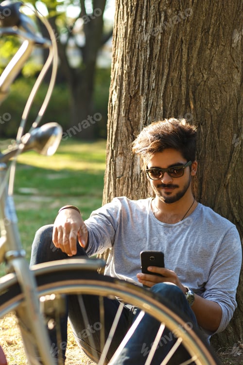 Preview: Portrait of young man with bicycle relaxing in park.