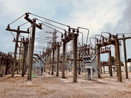 Preview: Electrical substation with high voltage power lines and transformers under a blue cloudy sky