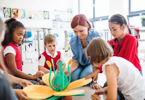 Preview: A group of small school kids with teacher sitting on the floor in class, learning