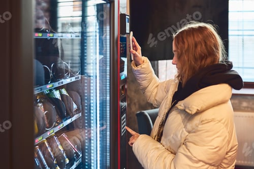 Preview: Woman paying for product at vending machine using contactless method of payment with mobile phone