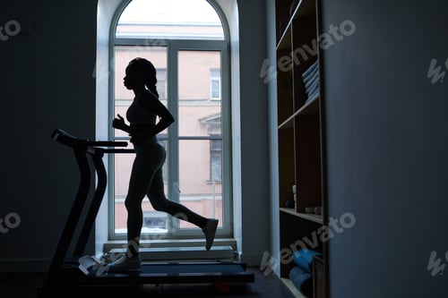 Preview: Silhouette of Woman Jogging on Treadmill by Window
