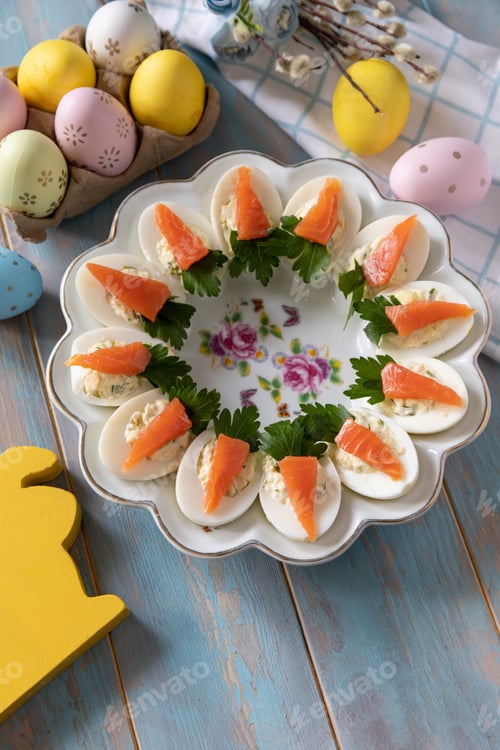 Preview: Stuffed eggs with cheese and salted salmon in the form of a carrot on a wooden table.