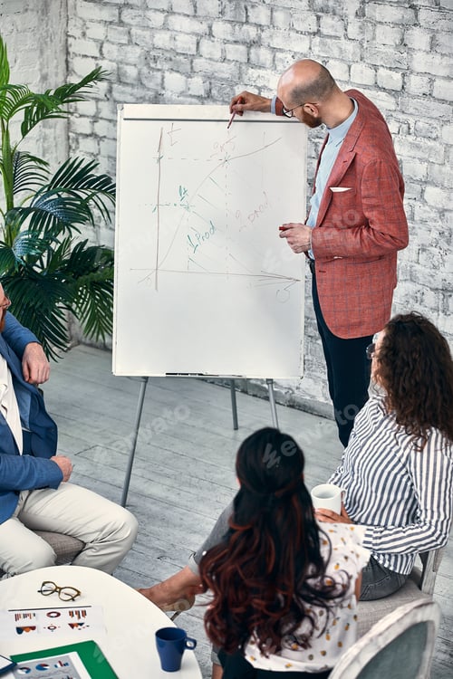 Preview: Confident businessman writing on flip charts presentation new project in boardroom at company