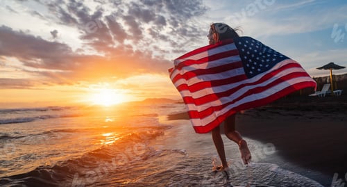 Preview: Happy woman smiling and running on beach with the US flag. July 4th independence day. Holiday