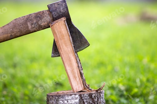 Preview: Close-up of strong muscular man hands cutting with old sharp iron ax through chunk of firewood