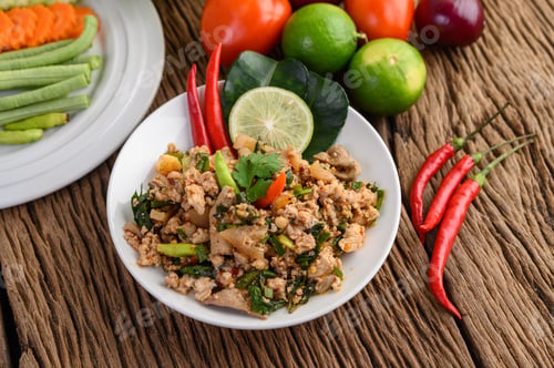Preview: Spicy Minced Pork Salad on a white plate on wooden table.