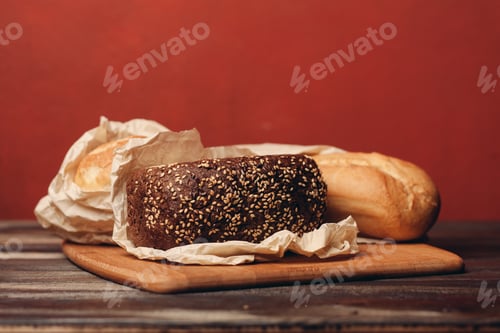 Preview: loaf of bread flour product on a tray on a wooden table and red background, pastries