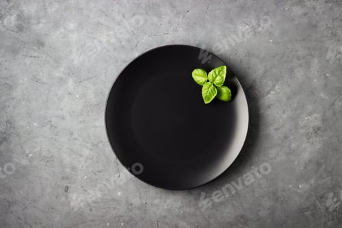 Preview: Table setting. Black plate over gray concrete background.