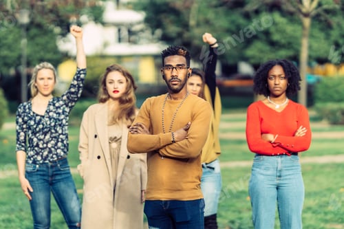 Preview: a man with African-American features looks defiantly at the camera, in front of four women.