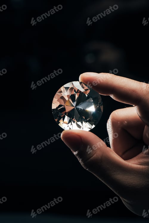 Preview: cropped view of man holding big clear shiny diamond on black background