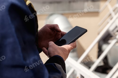 Preview: Industrial mountaineering worker in uniform using mobile phone device, social media and online work