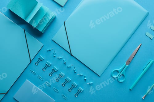 Preview: flat lay of paper binders and various arranged stationery isolated on blue